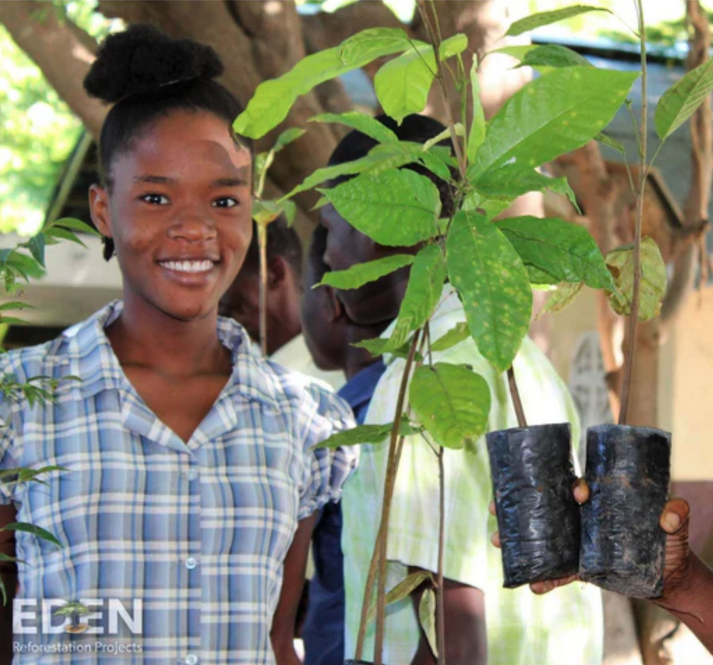 Eden reforestation project image of new tree saplings and a smiling young woman