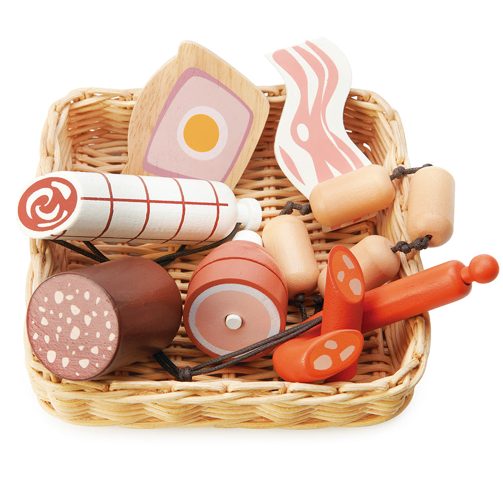 A hand crafted wicker basket with continental charcuterie set that is part of the market stall range. This set includes a slice of ham and egg pie, a black sausage, a rasher of bacon, a string of butchers sausages, a large salami, a spanish corizo style sausage, and a ham hock.